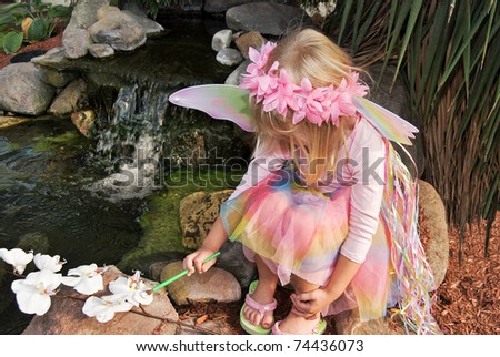 little fairy girl painting an orchid by waterfall