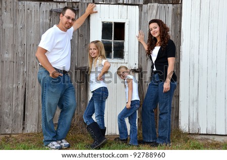 american middle class family posing by old barn