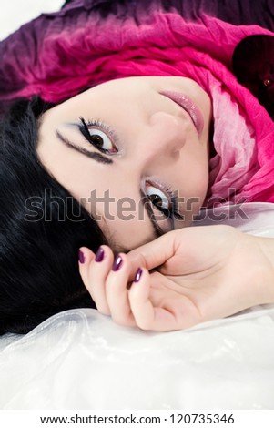 Wellness. Cosmetics. Portrait of beautiful woman model lying on the white fabric