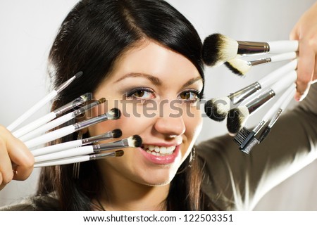 Beautiful woman with makeup brushes near her face