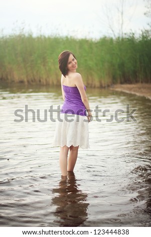 Young woman wading out of fresh water lake