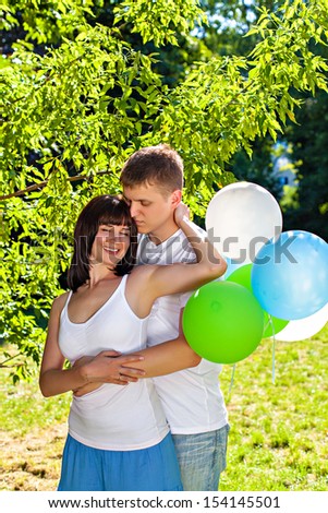 Young couple embracing and holding bunch of balloons