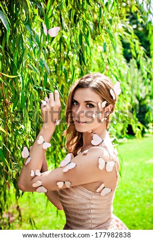 Beautiful young female with many butterflies on her face and hands