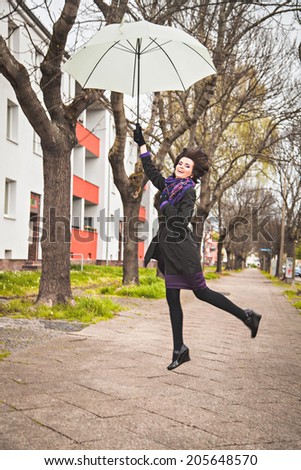 Happy young woman flying with umbrella
