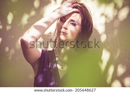 Pensive woman standing in shadow of tree