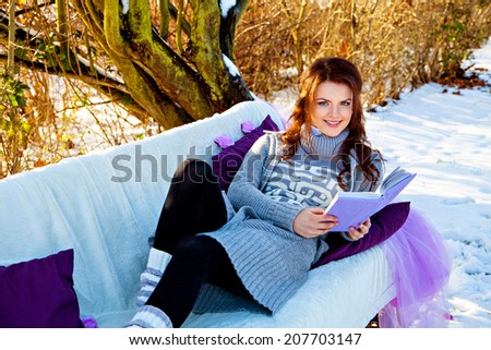 Woman reading book at winter forest lying on the couch