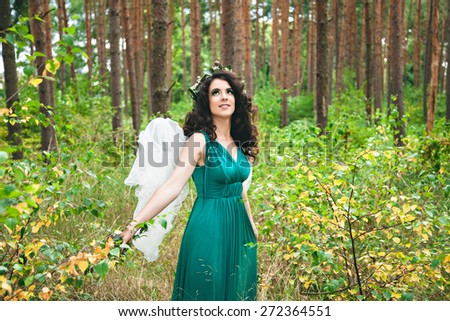 Pretty girl with angel wings looking up in the forest
