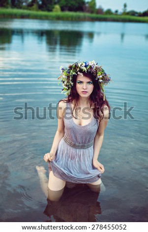 Young beautiful drowned woman in grey dress lying in the water