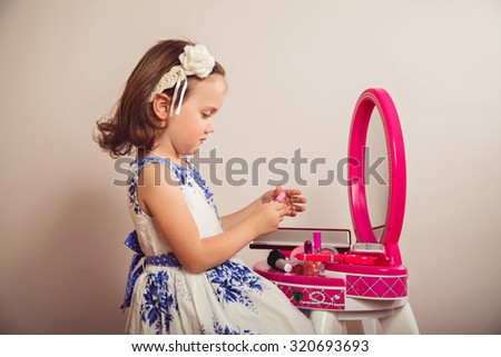 Little princess with nail polish in front of a mirror of beauty table