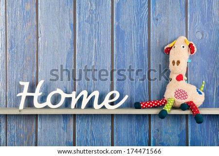 Stuffed animal Giraffe sitting against blue wooden background at home