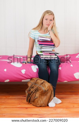 Fourteen year old girl with many school books and too many homework