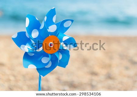 Blue and white windmill toy at the beach