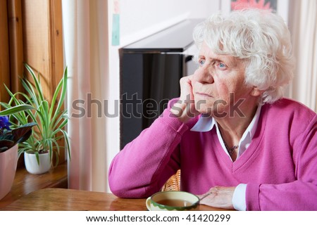 Elderly lonely woman depressed sitting at the table