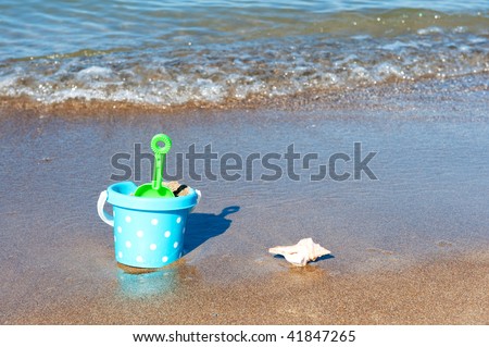 Beach vacation with bucket and plastic toys in the water