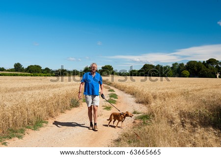 Elderly man is walking the dog in free nature