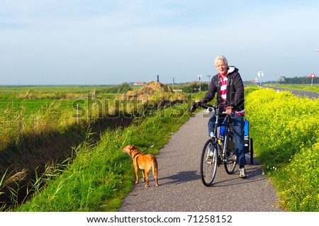 Man with his dog at the bike in Dutch landscape