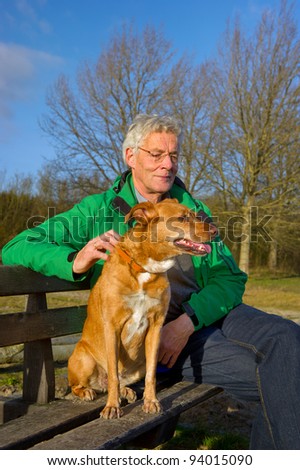 Man with dog sitting on a bench in winter sun