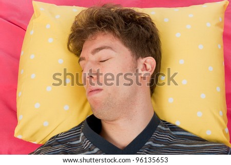 Man sleeping in bed with head on yellow pillow
