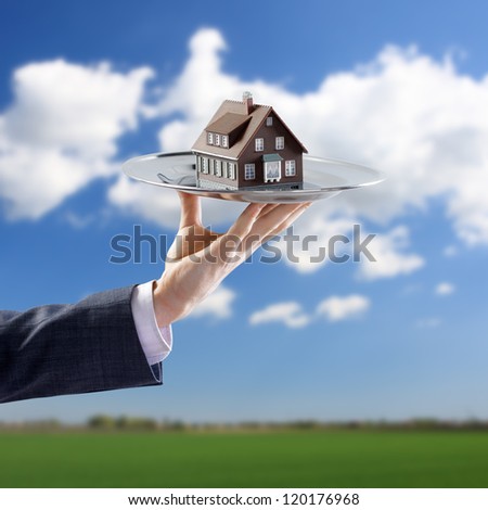 Real estate offer. Businessman holding a silver tray with an artificial model of the house