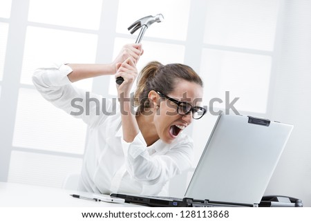Freaked out business woman with a hammer ready to smash her laptop computer