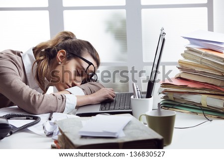 Tired businesswoman sleeping on the desk, in front of the computer screen.