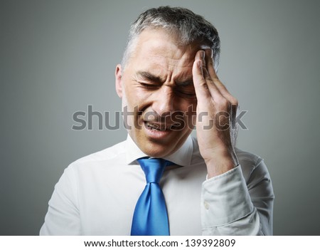 Attractive mature business man in pain holding her head