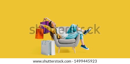 Cheerful happy shopaholic woman with lots of shopping bags, she is sitting on an armchair and celebrating, blank copy space Foto stock © 