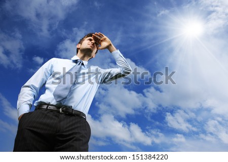 Young Business man looking away against blue sky