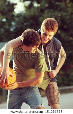 Two friends playing a game of basketball on an outdoor court.