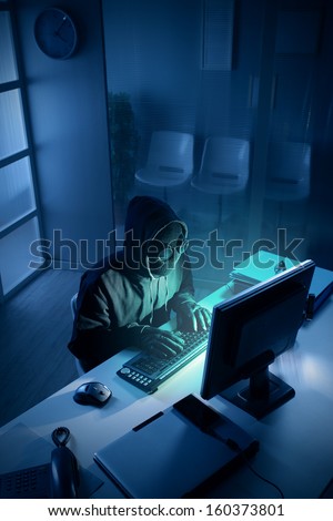 Young male thief stealing data from computer