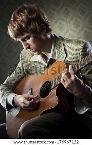 Vintage guy playing acoustic guitar and singing on retro wallpaper.