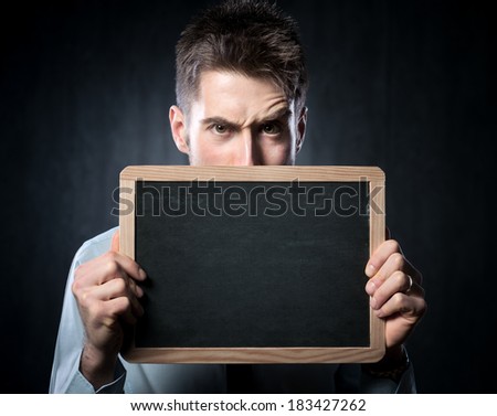 Young handsome man with raised eyebrows holding a blackboard.