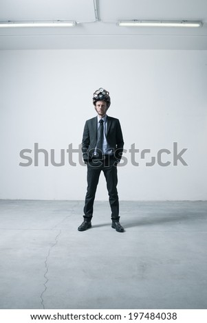 Confident businessman standing in an empty room with futuristic helmet.