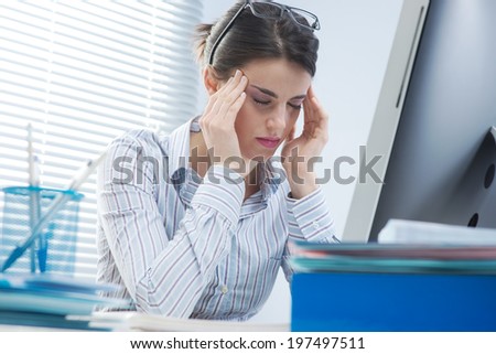 Tired office worker with headache touching her temples.