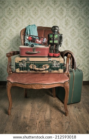 Family holiday packing with vintage suitcases and toys on elegant red velvet armchair.