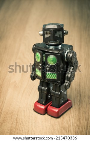 Vintage funny tin toy robot on hardwood floor looking at camera.