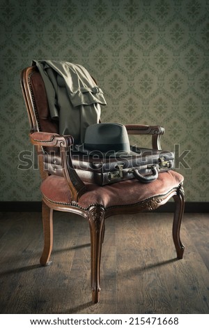Vintage businessman clothing and briefcase on retro chair and vintage wallpaper on background.