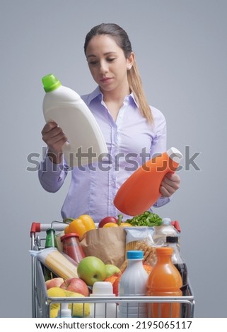 Woman doing grocery shopping at the supermarket and comparing products, she is checking two bottles of laundry detergent Stock foto © 