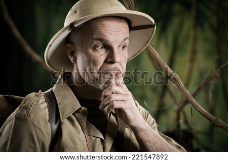 Retro adventurer in the jungle thinking with hand on chin.