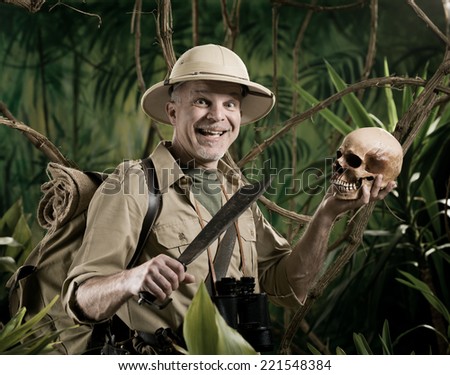 Smiling explorer in the jungle holding skull and machete.