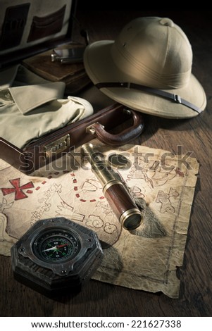 Old treasure map with colonial style pith hat, bras telescope and compass.