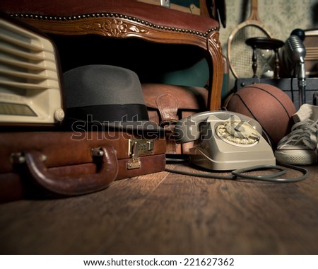 Group of vintage objects on attic hardwood floor, including old toys, phone and sports items.