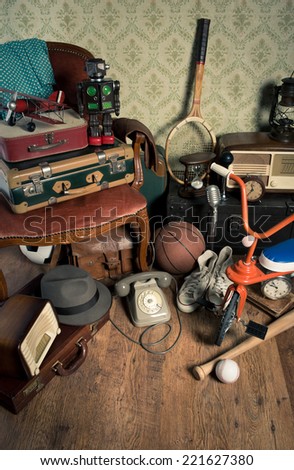 Group of vintage assorted items on attic hardwood floor with vintage wallpaper background.