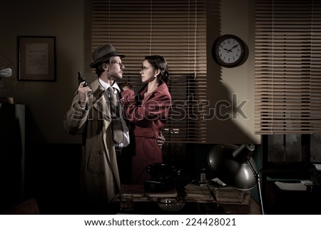 Passionate vintage couple embracing in detective\'s office holding a gun.
