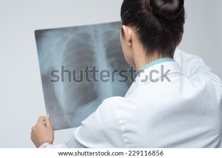 Confident female doctor examining accurately a rib cage x-ray.