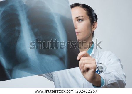 Confident female doctor examining accurately a rib cage x-ray.