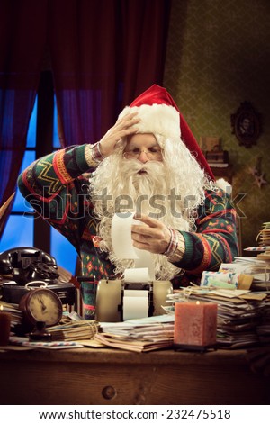 Santa Claus accountant checking a long bill and using a vintage calculator on his messy desk