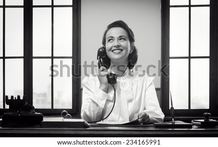 Smiling vintage receptionist working at office desk and smiling