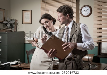 Young secretary on the phone and director working together, 1950s vintage style office.