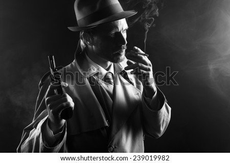 Film noir: attractive gangster in trench coat smoking a cigarette and holding a revolver